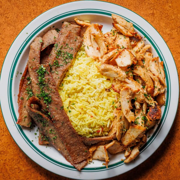 A white plate with green stripes holds yellow rice, sliced gyro meat, and chopped chicken.